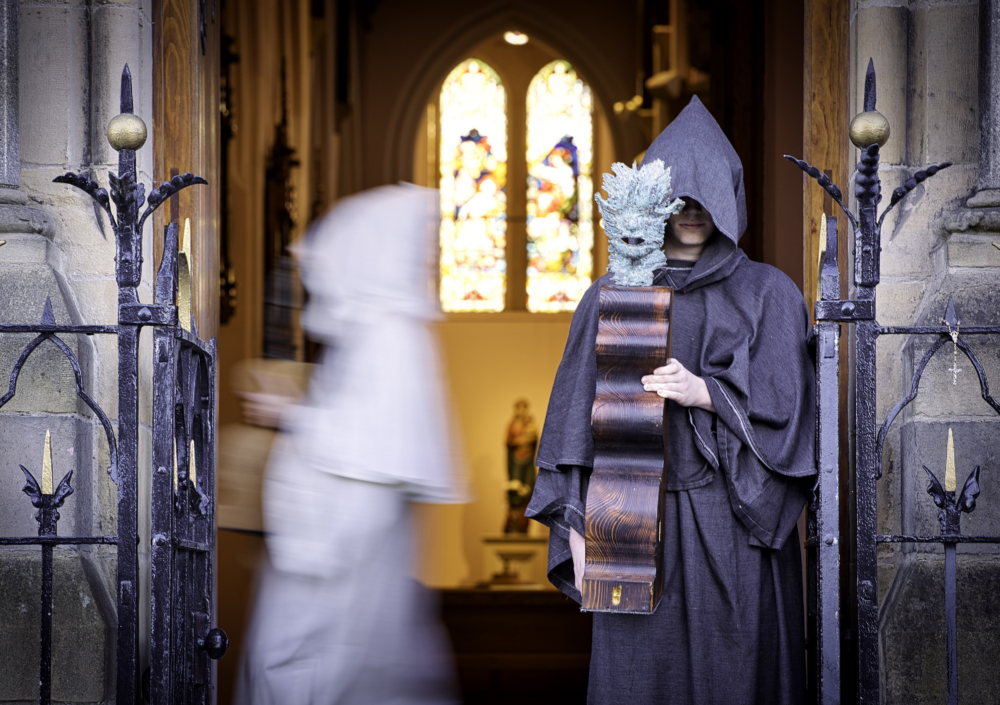 Large chess board with pieces made of carved wood and smaller figures made of copper.